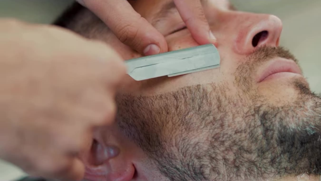 A straight razor shaping the cheek line of a beard
